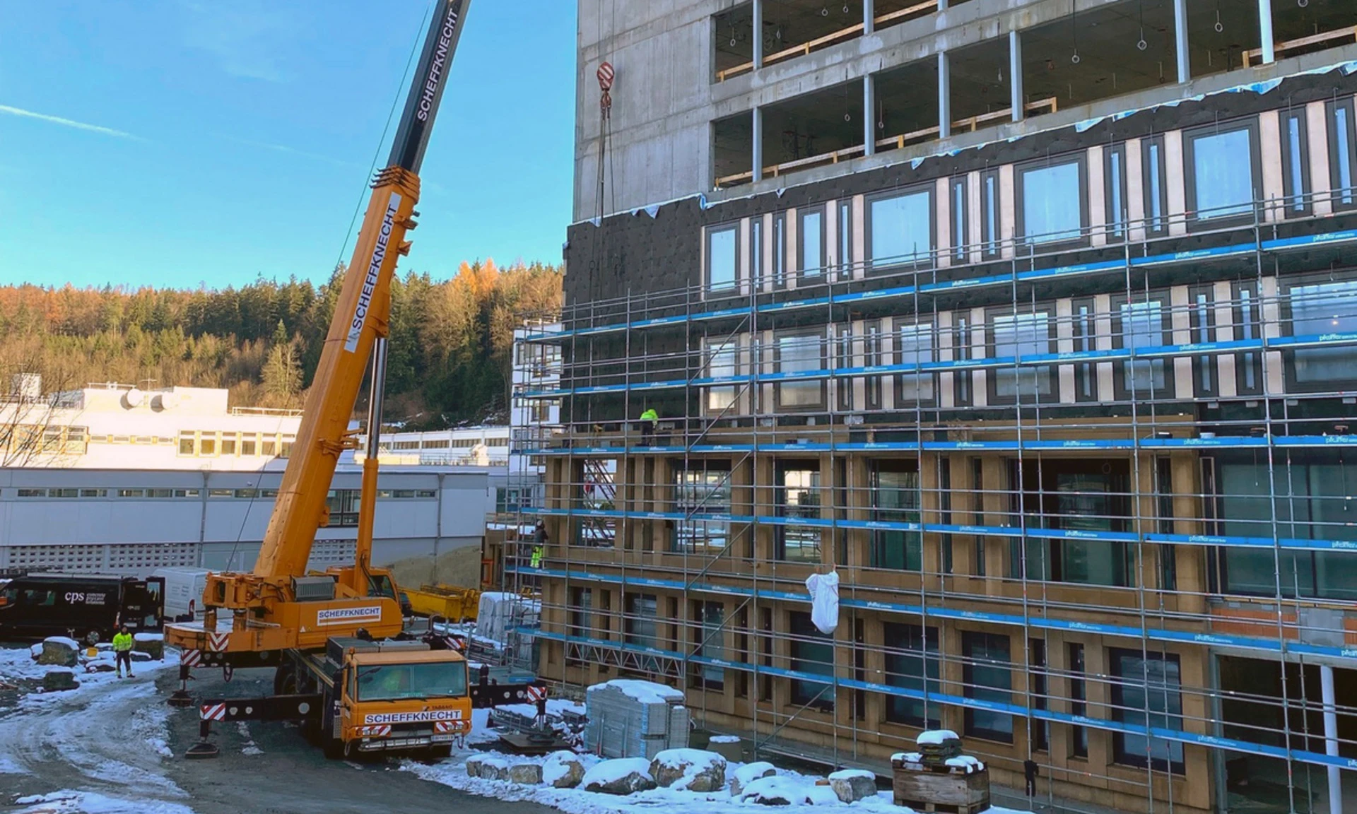 Ein Fassadenelement aus Beton wird mittels Mobilkran und Monteuren am Gebäude des neuen LKH in Rankweil eingebaut.