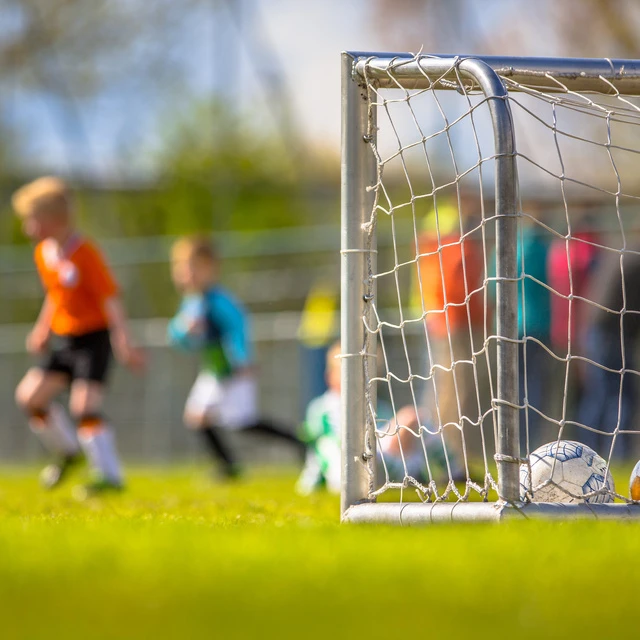 Kinder spielen Fußball und ein Tor ist zu sehen.