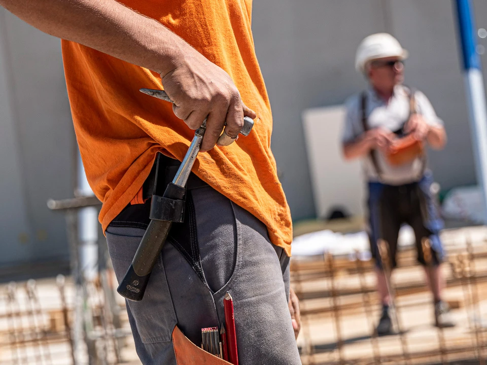 Bauarbeiter zieht einen Hammer aus seiner Hosenhalterung