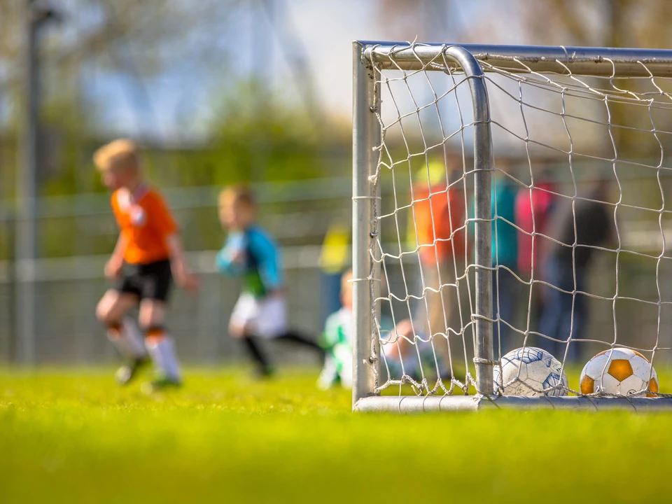 Kinder spielen Fußball und ein Tor ist zu sehen.